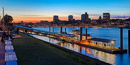 Pier for the harbour ferries at the Stage Theater on the Elbe in the evening in front of the city skyline