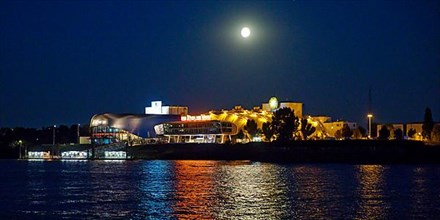 Atmospherically illuminated Stage Theater with the Elbe in the evening with full moon