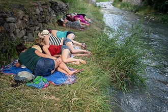 Group of people take a nap by the river at Pirineos Sur International Festival of Cultures in Sallent de Gallego