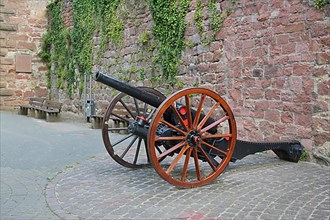 Historical cannon with wagon wheels in front of the town wall in Eberbach