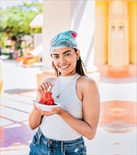Portrait of smiling girl holding shaved ice in the street. Young woman holding a cup of shaved ice on the street. Concept of a girl with a Nicaraguan raspado. ICE SHAVING from Nagarote