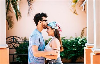 Man kissing his girlfriend forehead outside. Cute couple embracing the boyfriend kisses the girl forehead. Portrait of beautiful couple in love. Boyfriend tenderly kissing his girlfriend forehead