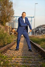 Mafia boss in blue suit on railway tracks