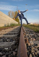 Drunk man in suit balancing over railway tracks at the harbour