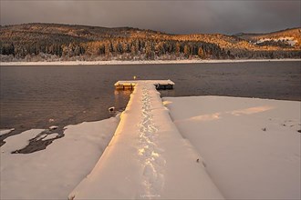 Snow-covered footbridge with footprints