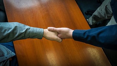 Close-up overhead shot of two men shaking hands. Concept of deal