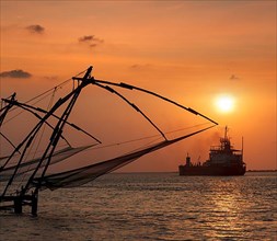 Kochi chinese fishnets on sunset and modern ship. Fort Kochin