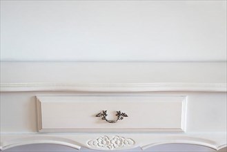 Close up of a white classic console over a white wall