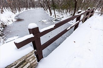 Rustic bridge over frozen river in winter