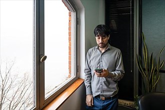 Latino businessman working in an office overlooking the river using the phone