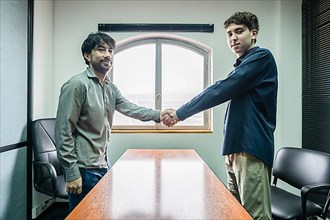 Office men shaking hands looking at the camera. Concept of deal