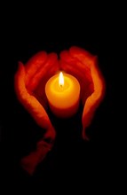Wax candle burning between 2 hands