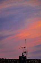 Antenna mast in front of red-blue sky at sunset