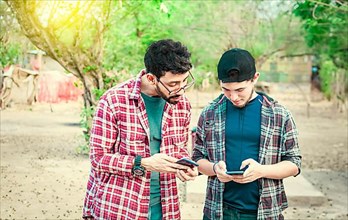 Two teenage guys pointing and checking their cell phones