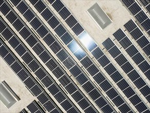 Aerial view of solar panels mounted on roof of large industrial building or warehouse