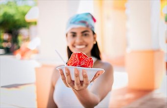 Smiling girl holding shaved ice on the street. Close up of young woman holding a shaved ice in the street. Concept of a girl with a Nicaraguan raspado