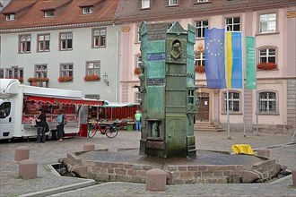 Minster fountain by Klaus Ringwald 1989 at the market place during the weekly market market in front of the town hall with EU flag and Ukrainian flag