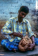 A man carving monkey on the shell of coconut