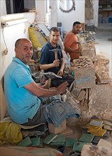 Moroccan cellular craftsmen at work: hammering small pieces out of a tile