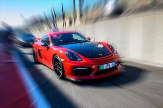 Dynamic photo with zoom effect of sports car racing car red Porsche Cayman GT4 leaving pit lane