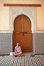 Moroccan woman in front of a traditional wooden gate
