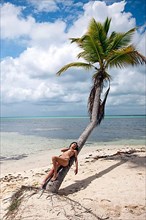 Woman leaning against palm tree