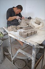 Moroccan potter at work: turning at the potter's pane and shaping ceramic vessels and pottery: Jugs