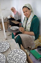 Moroccan woman painting plates and bowls in the workshop