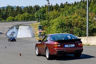Historic sports car Porsche 944 Turbo Oldtimer Classic Car starts to keep control at slalom course at driving safety training