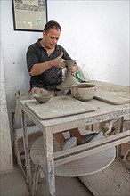 Moroccan potter at work: turning at the potter's pane and shaping ceramic vessels and pottery: Jugs
