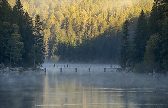 Bridge over the Eibsee lake with fog in the morning