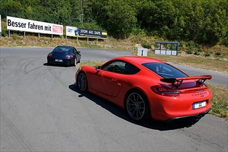 Two sports cars in front red Porsche Cayman GT4 with rear spoiler in the background Porsche 911 996 Carrera on course of driving safety training