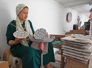 Moroccan woman painting plates in the workshop