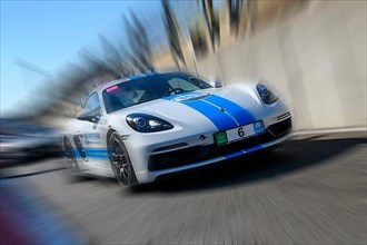 Dynamic photo with zoom effect of sports car racing car white with blue stripe Porsche 718 Cayman GTS leaving pit lane