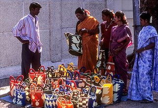Women haggle with a vendor of plastic crochet wire bags at Coimbatore