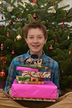 Boy with presents in front of Christmas tree