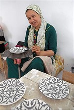 Moroccan woman painting plates in the workshop