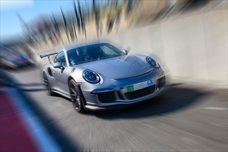 Dynamic photo with zoom effect of sports car racing car grey silver Porsche 911 GT3 leaving pit lane