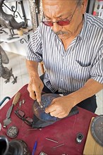 Moroccan man hammers a silver thread onto a metal plate