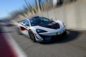 Dynamic photo with zoom effect of sports car racing car McLaren 620R leaving pit lane
