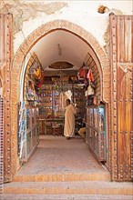 Moroccan man in a djellaba or traditional hooded cloak standing in a shop in the old town