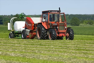 Volvo tractor with round baler and mechanical bale wrapper