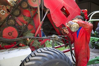 Farmers lubricate chain on round baler