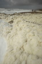 Sea foam washes up on the beach after a storm