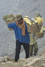Local men carry sulphur blocks in baskets on the slopes of the volcanic crater