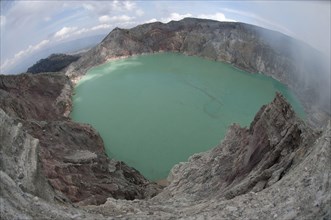 Turquoise-green coloured acidic volcanic crater lake with rising steam