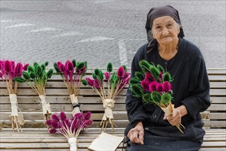 Georgian woman selling flowers on a bench