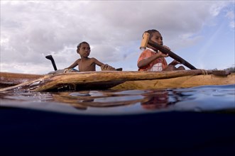 Boys rowing a canoe at sea