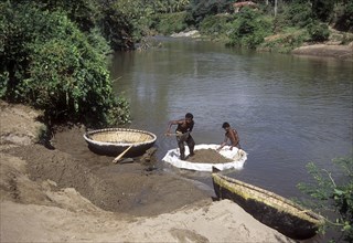 Collecting sand from river on coracle or parisal in Tamil Nadu