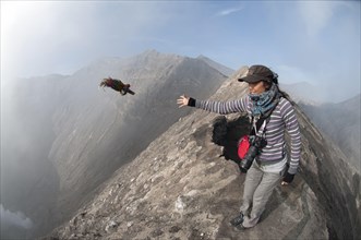 Tourist throwing offering into smoke vent of volcano